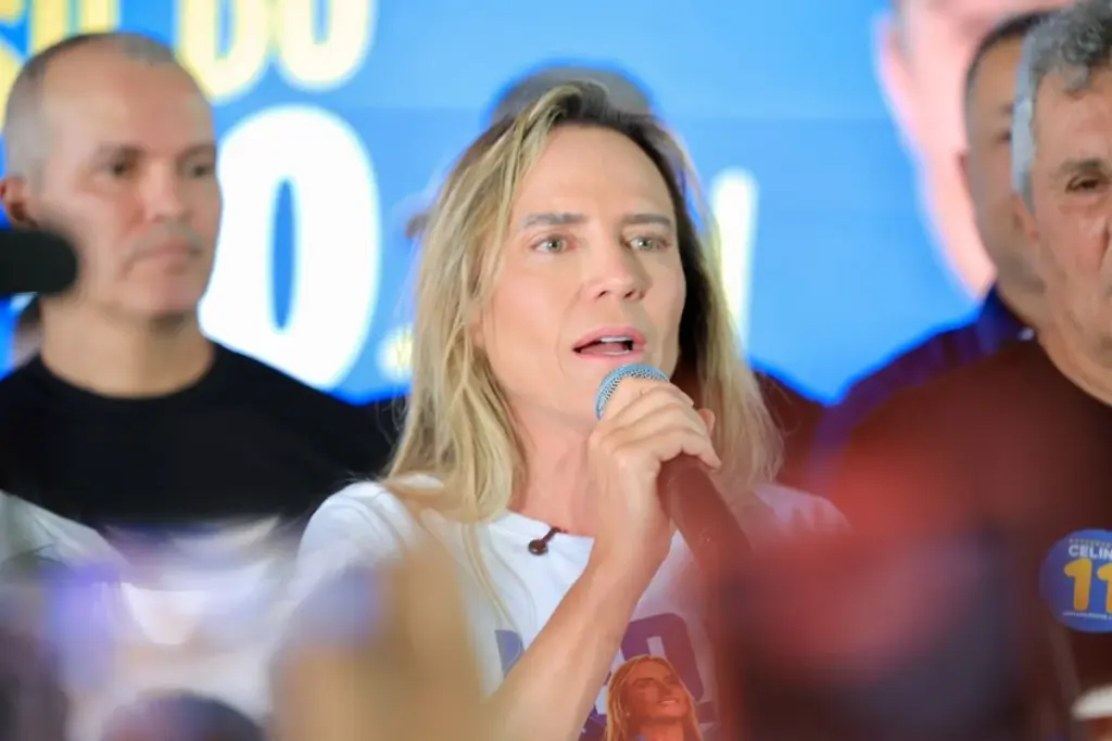 Celina Leão fala ao microfone, cercada de participantes.
