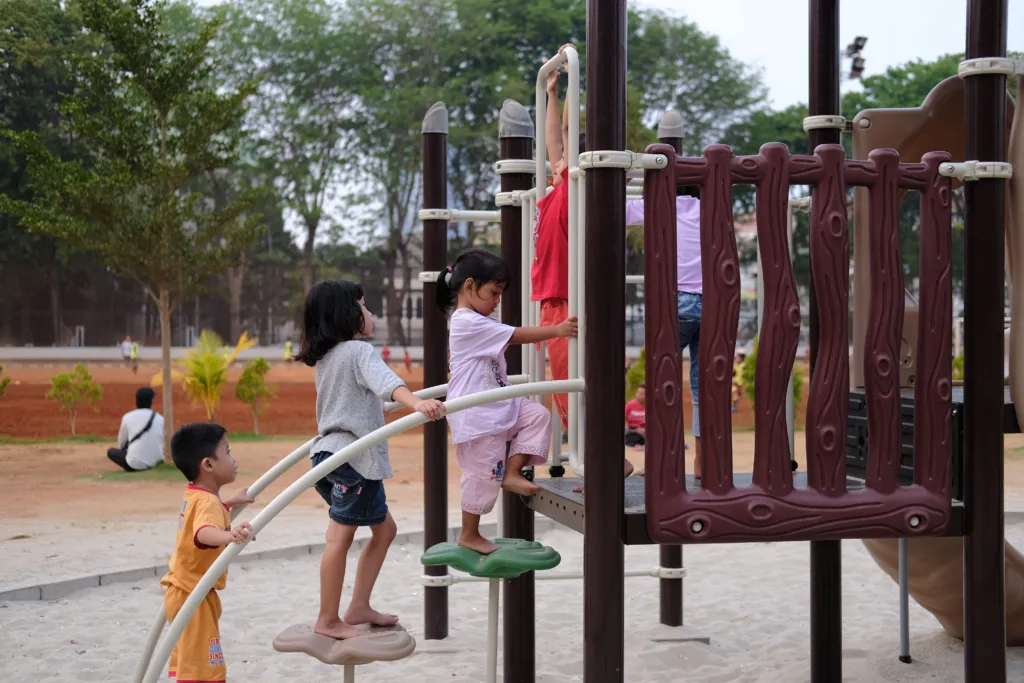 Grupo de crianças brincando e subindo em equipamentos de um parque ao ar livre