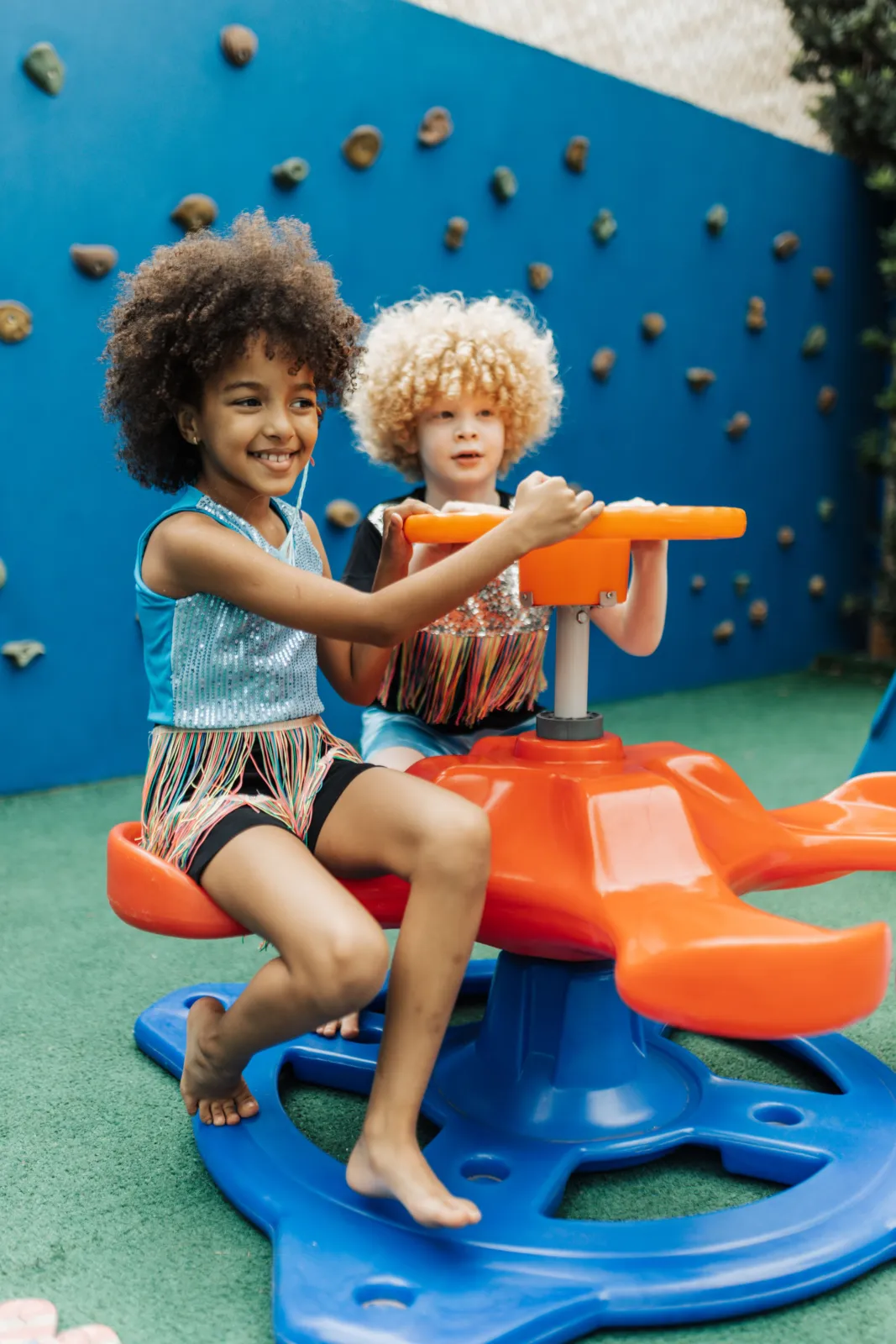 Duas crianças brincam em brinquedo giratório colorido no parque