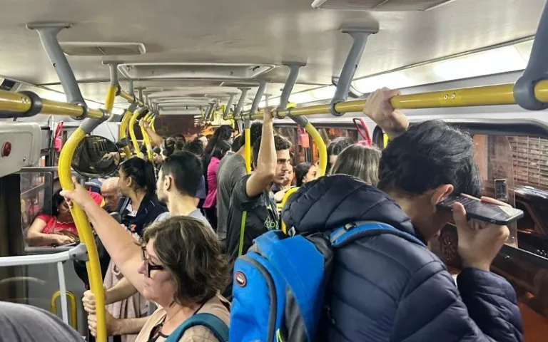 Passageiros em pé seguram barras amarelas dentro de um ônibus em Novo Hamburgo, em fotografia horizontal de arquivo.